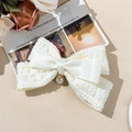 Detail of a creamy lace and satin bow hair clip with a delicate pearl pendant accent - Beige