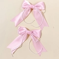 Dettaglio di due fermagli per capelli a fiocco in raso rosa con catenelle di perle bianche - Rosa (Coppia)
