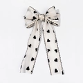 Detail of a mesh hair bow clip with black heart patterns and wavy stitched edges - White (Spring Clip - With Streamers)