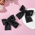 Paar elegante schwarze Satin-Haarschleifen mit Rüschenkanten auf rosa Hintergrund - Schwarz