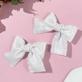 Detail von weißen Satin-Haarschleifen mit Rüschenkanten und weicher Stofftextur - Weiß