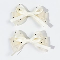 Dettaglio di due fermagli per capelli in raso crema con tulle a pois neri e fiocchi - Beige