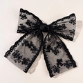 Dettaglio di elegante fermaglio a fiocco in pizzo nero con trama a rete in stile francese - Nero