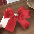 Détail d'une pince à cheveux en satin rouge avec centre en strass et perles rétro - Rouge