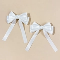 Nahaufnahme cremefarbener Satin-Haarspangen mit doppelten Bändern und glänzender Textur - Weiß