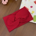Close-up of red knotted elastic baby headband on a dark wooden textured background - Red