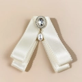 Dettaglio fiocco in raso crema con centro in cristallo e pendente elegante in perla - Beige