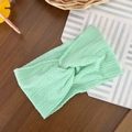 Detail of mint green cable-knit baby headband with twisted knot design on wooden background - Mint Green