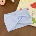 Detail of light blue twisted baby headband made of soft stretch fabric on wooden background - Blue