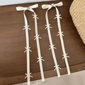 Detail view of cream ribbon hair clips with heart rhinestones and multiple small bows - Beige