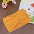 Detail of soft bright orange knotted elastic headband for baby on a wooden background - Orange