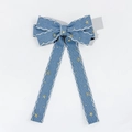 Detail view of denim bow hair clip with white wavy embroidery and gold stars - Light Blue