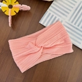 Detail of soft pink cable-knit baby headband with twisted knot on wooden background - Peach