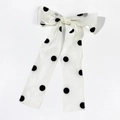 Detailed view of a white organza bow hair clip with classic black polka dots and long ribbons - Beige