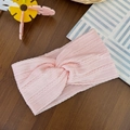 Detalle de diadema de punto rosa para bebé con textura trenzada sobre madera café - rosa fuerte