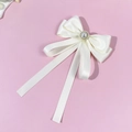 Detail of elegant cream satin bow with center pearl and gold beads on pink background - Beige