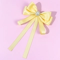Detail of yellow satin bow tie with central pearl and rhinestones on pink background - Yellow
