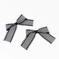 Detailed top view of black and white checkered bow hair clips with lace trim edges - Black