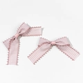 Detail of pink and white checkered bow hair clips with fringe edges on white background - Pink