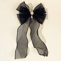 Dettaglio del fiocco in tulle nero con perla centrale e strass brillanti sulla clip - Nero