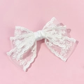 Détail d'un nœud à cheveux en dentelle blanche avec bords festonnés et ruban central - Blanc