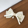 Dettaglio del fermaglio a fiocco in pizzo floreale con perle dorate e ciondolo a goccia - Fiocco Grande con Pendente / Beige