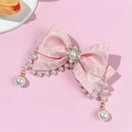 Gros plan sur barrette noeud en satin rose avec perles élégantes et détails glands - Rose