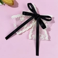 Détail d'une pince à cheveux en dentelle blanche avec nœud en ruban de soie noir élégant - Beige