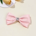 Detalle de pinza para el pelo con lazo rosa y cristal de corazón sobre fondo beige - Clip de Lazo Simétrico Corazón Strass (3#)