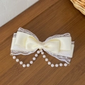 Cream Lolita bow hair clip with lace edges and elegant pearl tassels in a warm scene - Beige