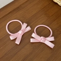 Set de dos gomas de pelo de satén rosa con lazo sobre fondo de madera para niñas - Rosa