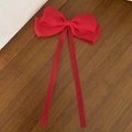Detail shot of a large red mesh ribbon hair clip with double long streamers on wood background - Red
