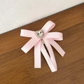 Sweet pink bow hair clip with a heart-shaped rhinestone on a natural wooden background - Pink