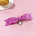 Detalle de un lazo de satén morado para el pelo con un colgante de corazón de diamantes - Rosa Rojo