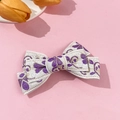 Dettaglio del fermaglio a fiocco in tessuto bianco con ricamo floreale viola e filo d'oro - Viola