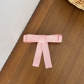 Close-up of pink satin bow hair clip with silk gloss on dark wood background - Pink