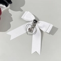 Dettaglio del fiocco in raso bianco con gemma a cuore nera e ciondolo a croce in argento - Bianco
