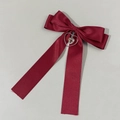 Detail einer burgunderroten Satin-Haarschleife mit Herz- und Kreuzanhänger - Burgunderrot