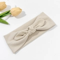 Detalle de diadema de punto acanalado beige con nudo decorativo sobre fondo blanco puro - Beige