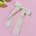 Detalle de un lazo de encaje crema con bordado floral sobre un fondo rosa intenso - Beige (Clip de Pelo)