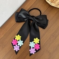 Detail van zwarte satijnen scrunchie met strik en kleurrijke geborduurde bloemaccenten - Zwart