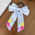 Vue détaillée du chouchou en satin bleu clair avec broderies florales sur fond bois - Bleu