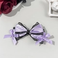 Détail macro du nœud à cheveux en satin lavande avec dentelle noire et motif artistique - Violet
