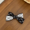 Dettaglio del fiocco per capelli bicolore con mini motivi a fiocco su fondo legno - Stampa a Fiocco Nero e Bianco (1#)