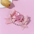 Detail of pink satin bow hair clip with fabric rose and pearl tassel on soft background - Pink
