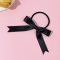 Detaillierte Nahaufnahme von schwarzem Satin-Haargummi mit Schleife auf rosa Hintergrund - Schwarz