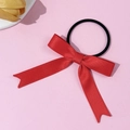 Elegant red satin bow hair tie with elastic black rope on a soft pink background - Red