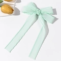 Detailed view of mint green ribbon hair bow with wavy edges and long elegant streamers - Green