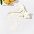 Detail of elegant ivory satin bow hair clip with long ribbons on a white background - Beige
