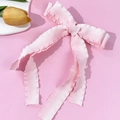 Detailaufnahme der rosa Schleifen-Haarspange mit Faltenkanten und strukturierter Textur - Rosa